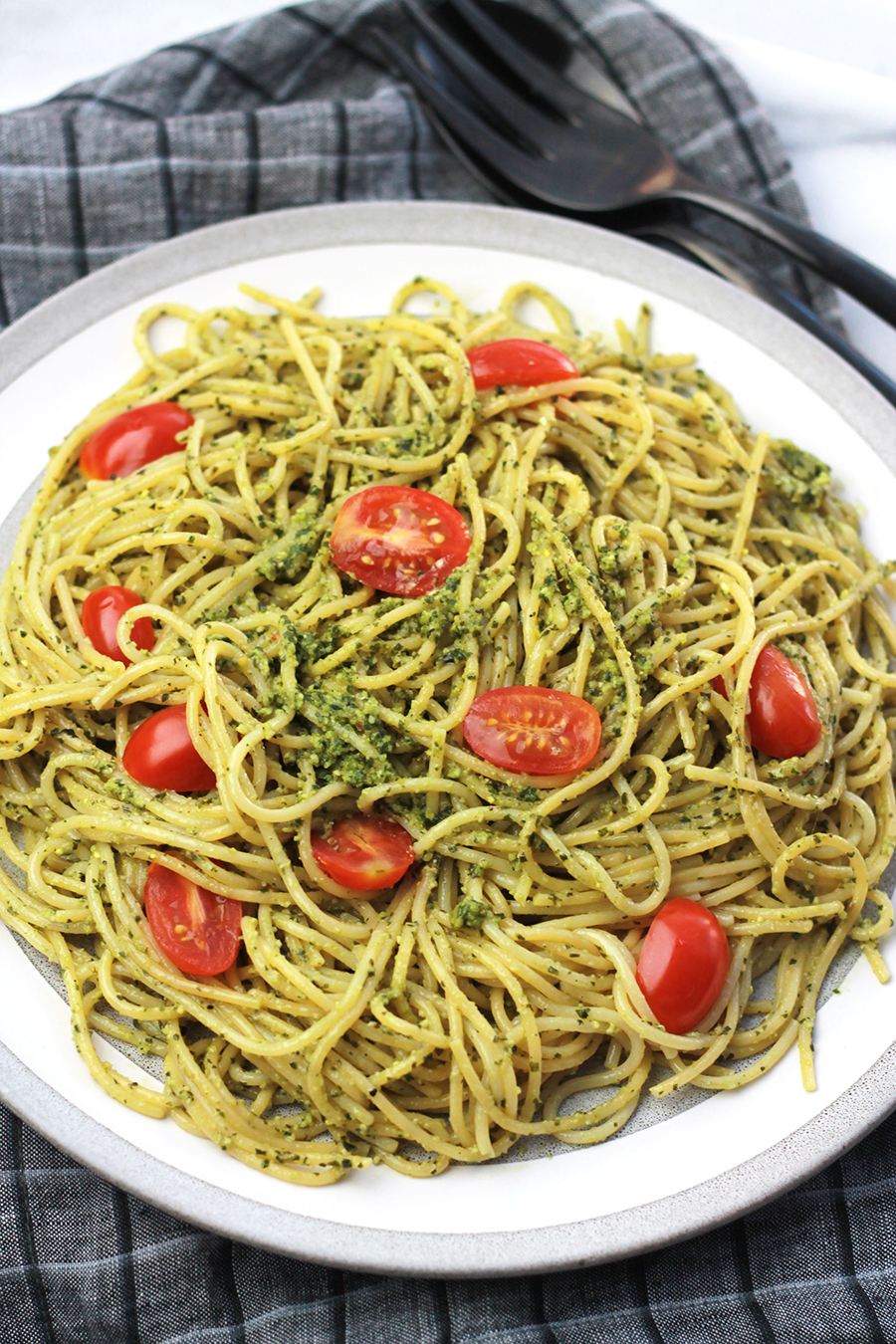 Plate of pasta tossed with Vegan Pesto with tomatoes on top.