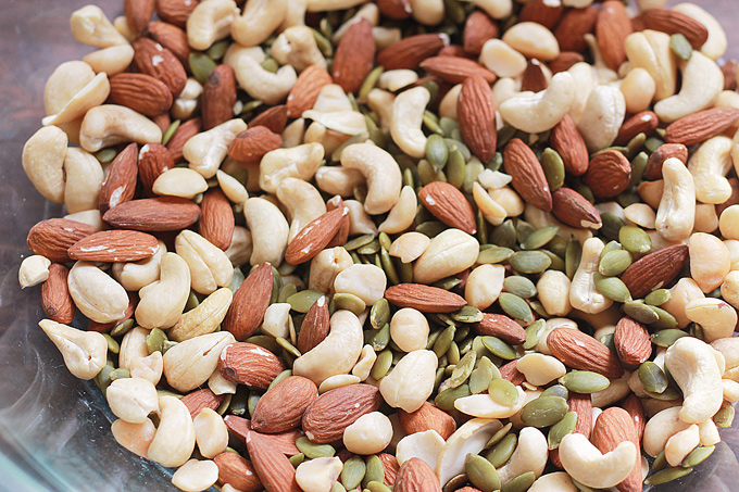 Close-up of mixed raw nuts in a glass mixing bowl.