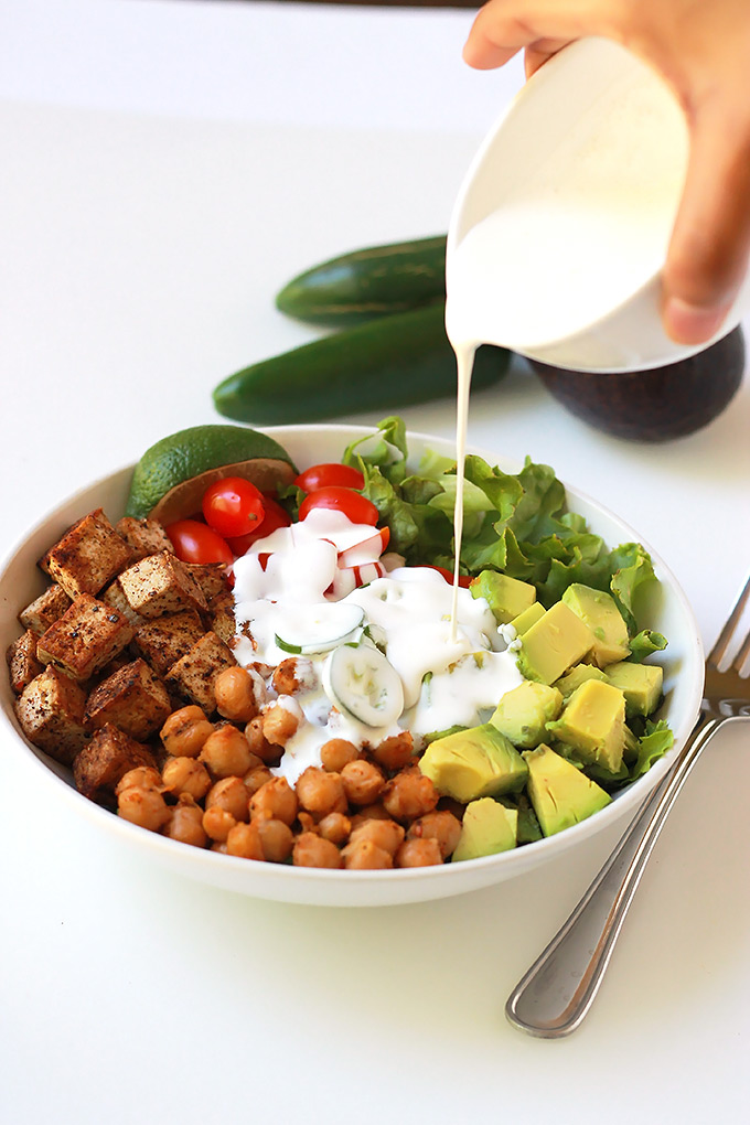 Pouring sauce over Spicy chickpea burrito bowl salad.