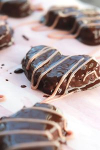 Hazelnuts, dates, and dark chocolate hearts, covered in more smooth creamy dark chocolate, drizzled with raspberry cream. Yum! Make these Chocolate Hazelnut Hearts for someone special, even if that someone special is you.