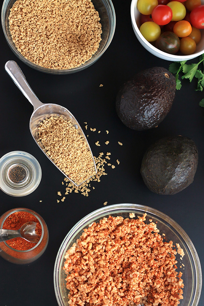 Overhead shot of dry textured vegetable protein, cherry tomatoes, avocados and bowl of hydrated textured vegetable protein.