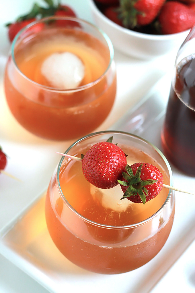 Overhead shot of two glasses filled with Sparking Strawberry Shrub garnished with whole strawberries on toothpicks.