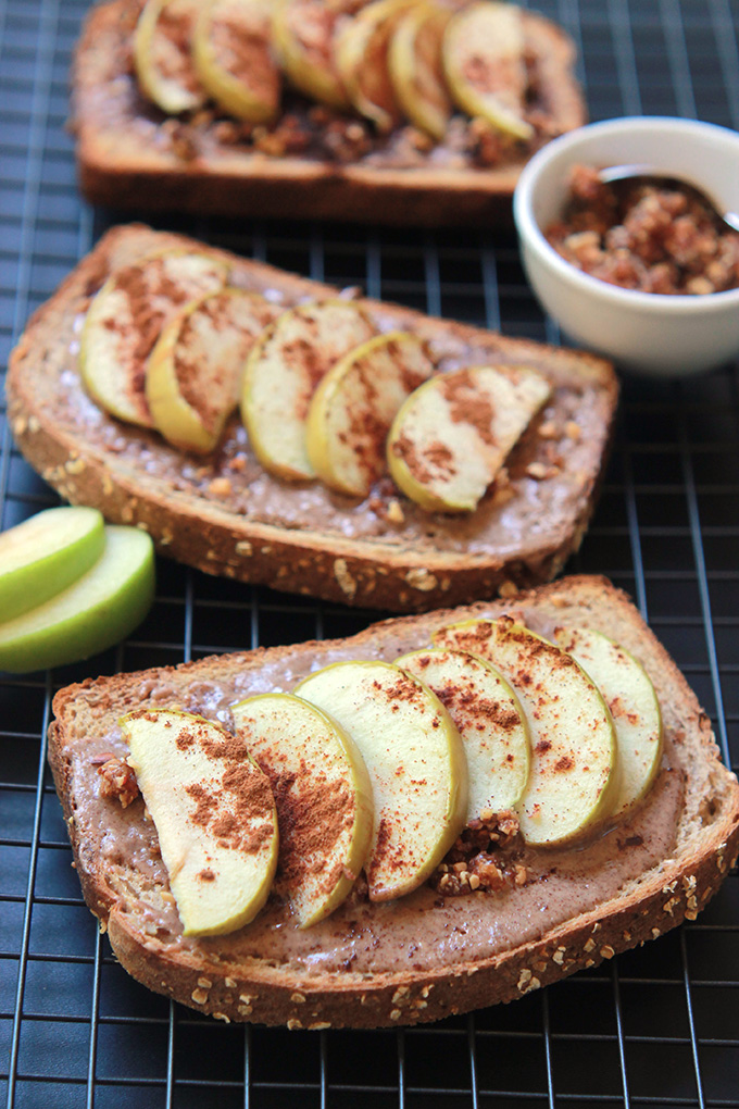 Whole wheat toast layered with almond butter, sliced apples, sprinkled ground cinnamon on cooling rack.