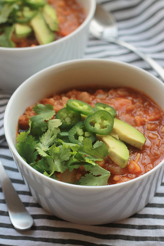 Close-up shot of Spicy Lentil Sweet Potato Stew with sliced avocado, jalapenos and cilantro. 