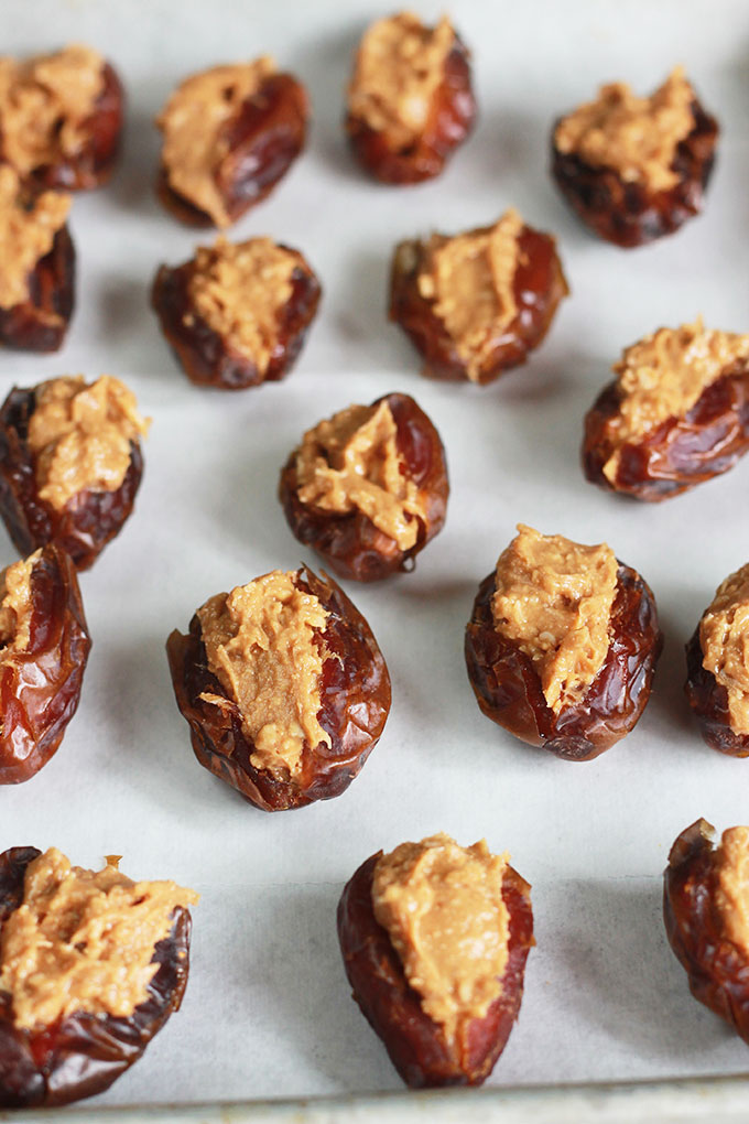 Dates stuffed with nut butter on parchment paper.