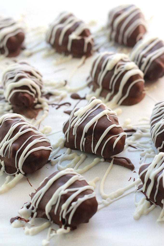 Close-up of Chocolate Covered Nut Butter Stuffed Dates on parchment paper.