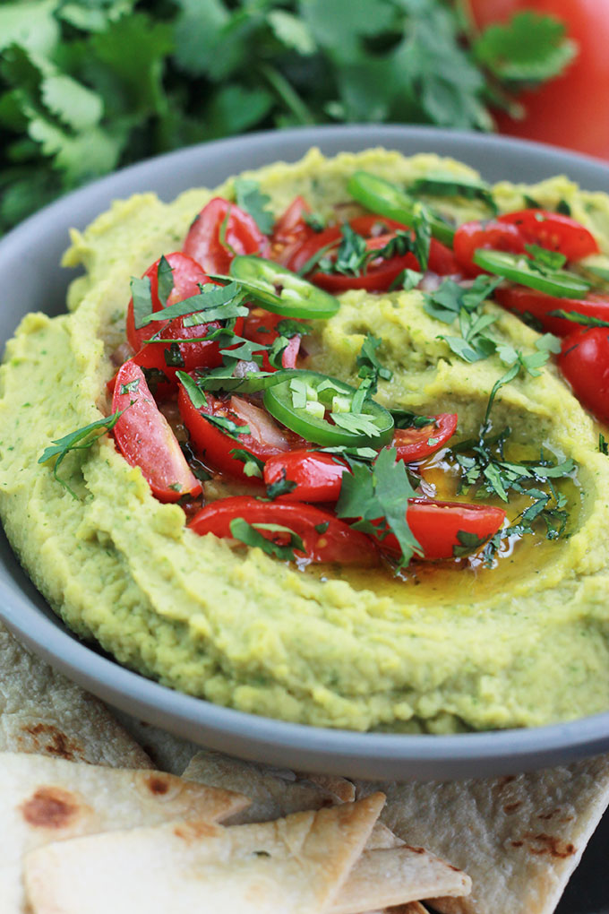 Bowl of Cilantro Jalapeno Hummus garnished with sliced tomatoes, jalapeno and cilantro.