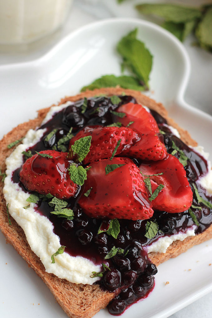 Lightly sweetened creamy lemon ricotta on toast topped with sweet juicy wild blueberry compote, sprinkled with mint. Sumptuosity on a plate.