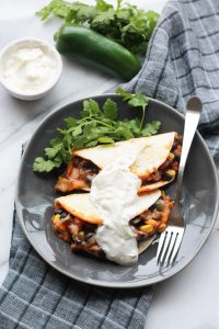 Baked Black Bean Tacos with Red Chile Sauce on plate with vegan sour cream