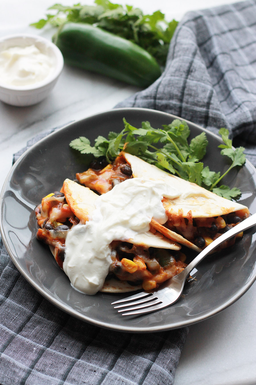 Baked Black Bean Tacos with Red Chile Sauce on plate topped with sour cream.