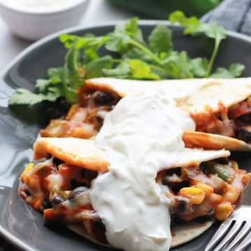 Baked Black Bean Tacos with Red Chile Sauce on plate topped with vegan sour cream