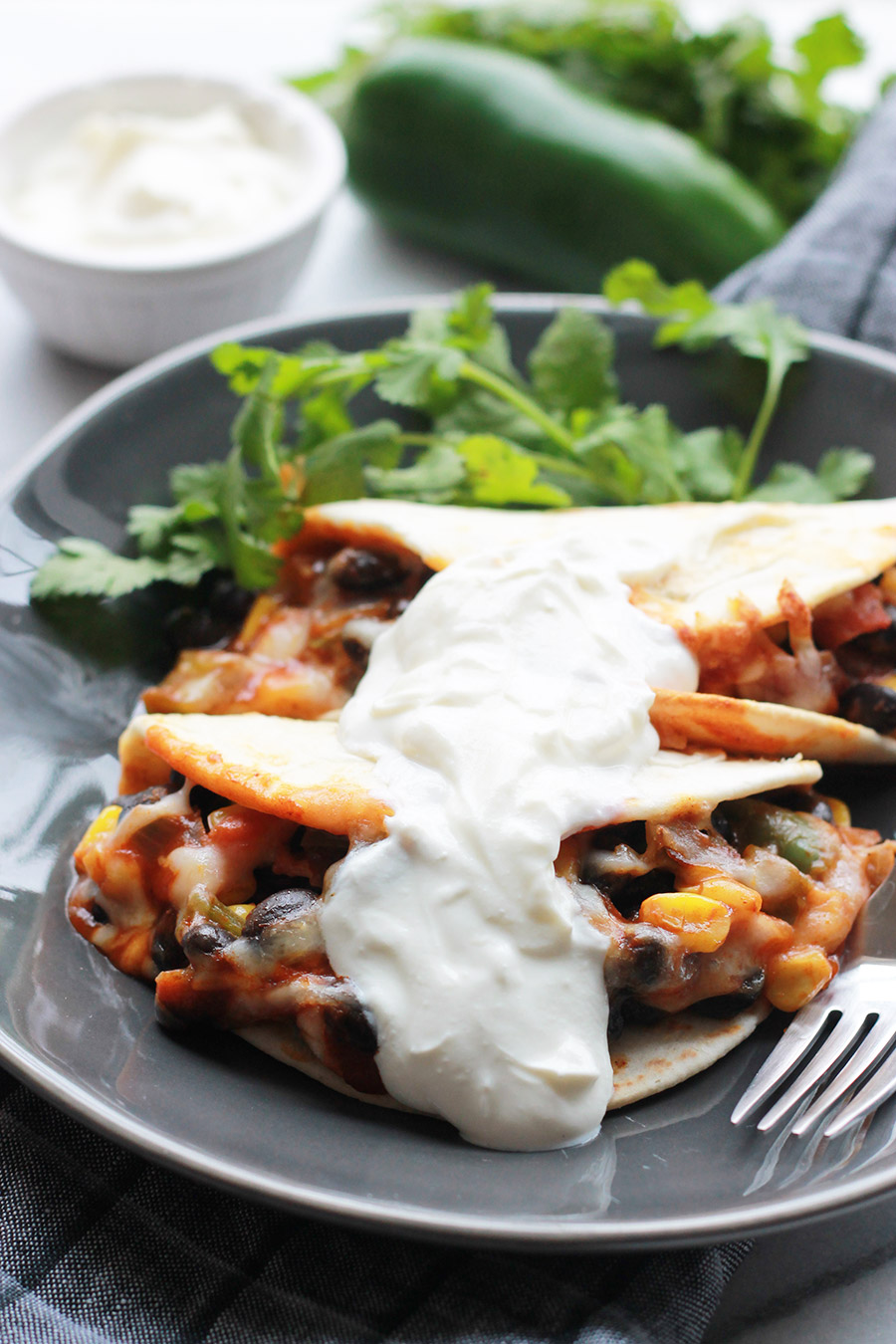 Baked Black Bean Tacos with Red Chile Sauce on plate topped with vegan sour cream