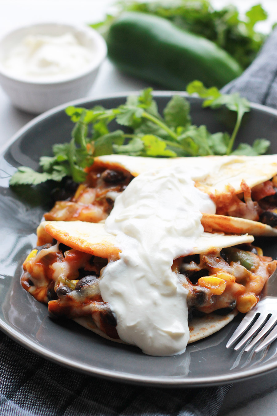 Baked Black Bean Tacos with Red Chile Sauce on plate topped with sour cream.