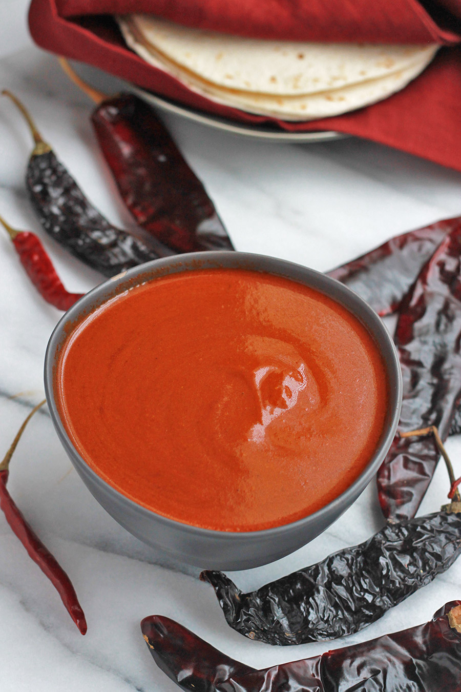 Red Chilies around a bowl of Red Chile Sauce.