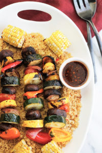 Overhead shot of Harissa Spiced Grilled Veggie Kabobs and corn over bed of couscous.