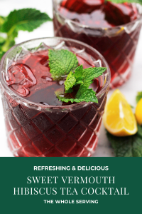 Two glasses filled with Hibiscus tea cocktail garnished with mint with lemon wedges on the side of glass
