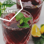 Two glasses filled with Hibiscus tea cocktail garnished with mint with lemon wedges on the side of glass