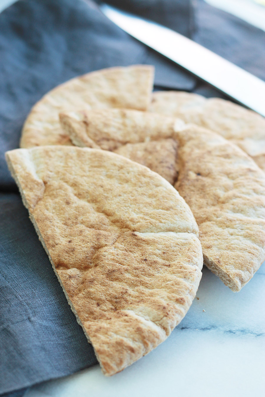 Slices of pita bread on blue napkin with knife in background.