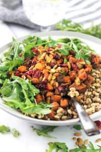 Bowl of grains with roasted butternut squash and arugula.