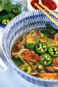 Close-up shot of Easy Vegan Tempeh Pho in blue and white bowl with chopsticks.