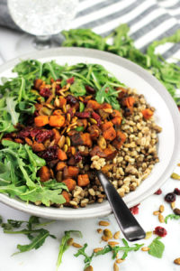 Bowl of grains with roasted butternut squash and arugula.
