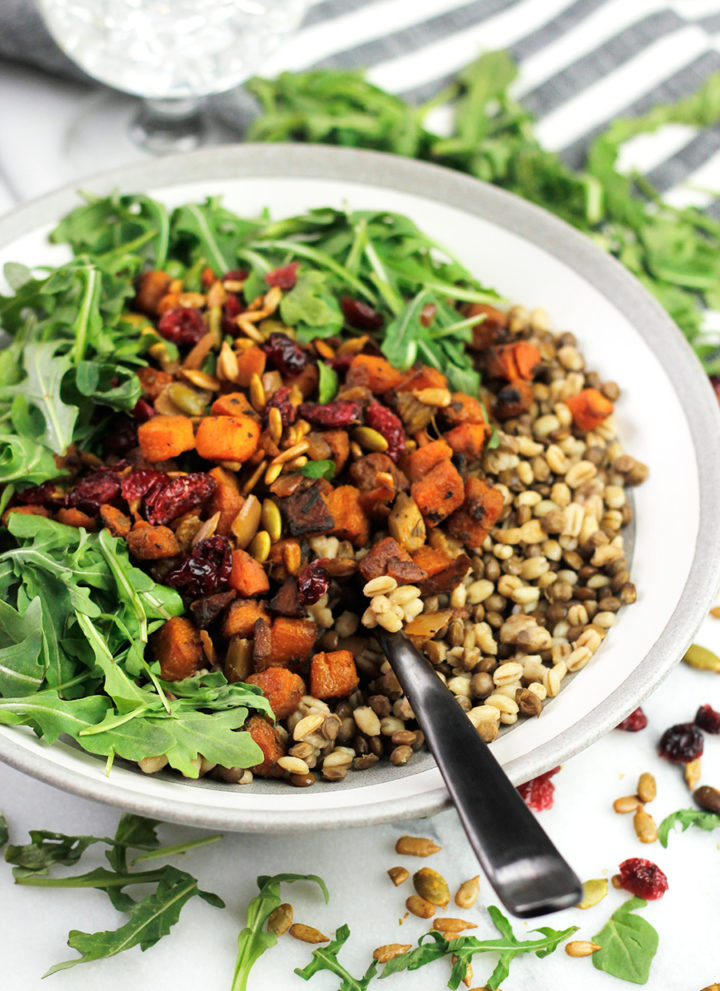 Bowl of grains with roasted butternut squash and arugula.