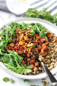 Bowl of grains with roasted butternut squash and arugula.