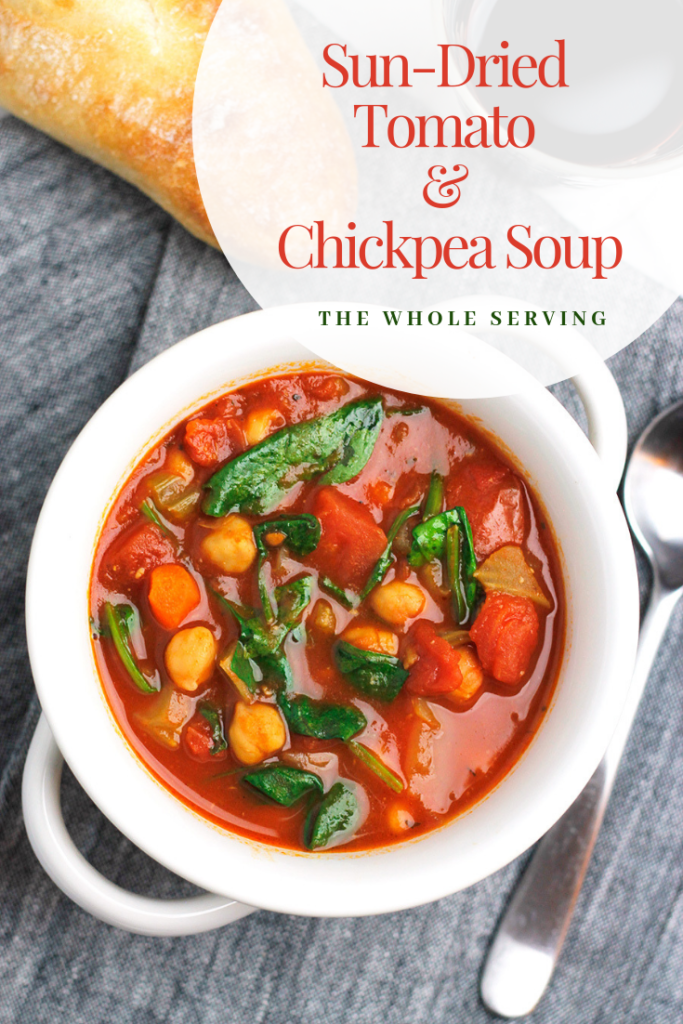 Overhead shot of Sun-Dried Tomato and Chickpea Soup with crusty bread and glass of red wine.