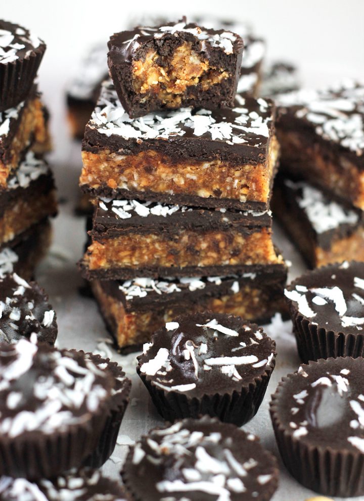 Angled shot of Coconut Cashew Chocolate Cups and a stack of Bars.