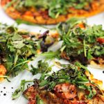 Slices of roasted veggie pizzas topped with arugula greens and drizzled with balsamic glaze.