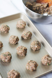 Uncooked meatless meatballs on shallow baking pan.