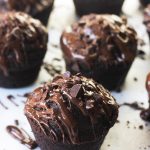 Close-up of Chocolate-On-Chocolate cupcakes drizzled with melted chocolate and sprinkled with chocolate pieces.