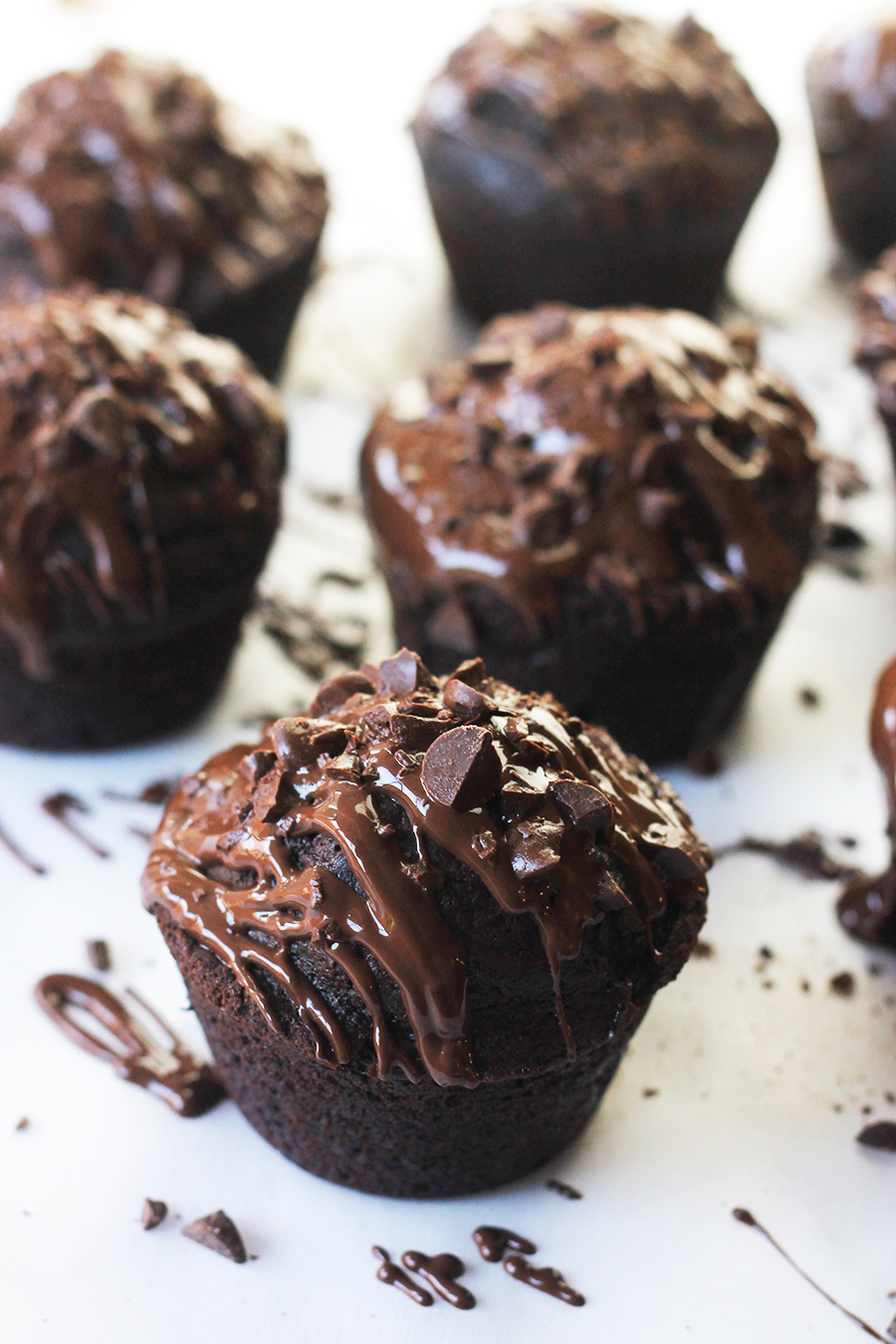 Close-up of Chocolate-On-Chocolate vegan cupcakes drizzled with melted chocolate and sprinkled with chocolate pieces.