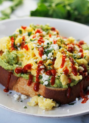 Avocado toast topped with soft scrambled eggs, crumbled queso fresco, fresh torn cilantro and drizzled with sriracha.