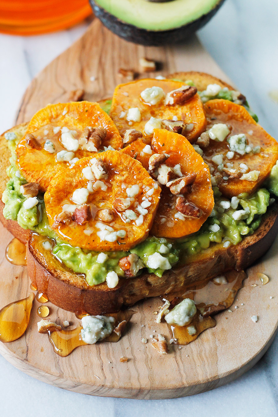 Avocado toast topped with roasted sweet potato rounds sprinkled blue cheese, pecans and drizzled with honey,