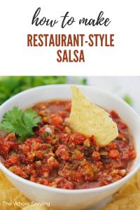 Bowl of salsa on a plate filled with tortilla chips and one tortilla chip dipped in salsa.