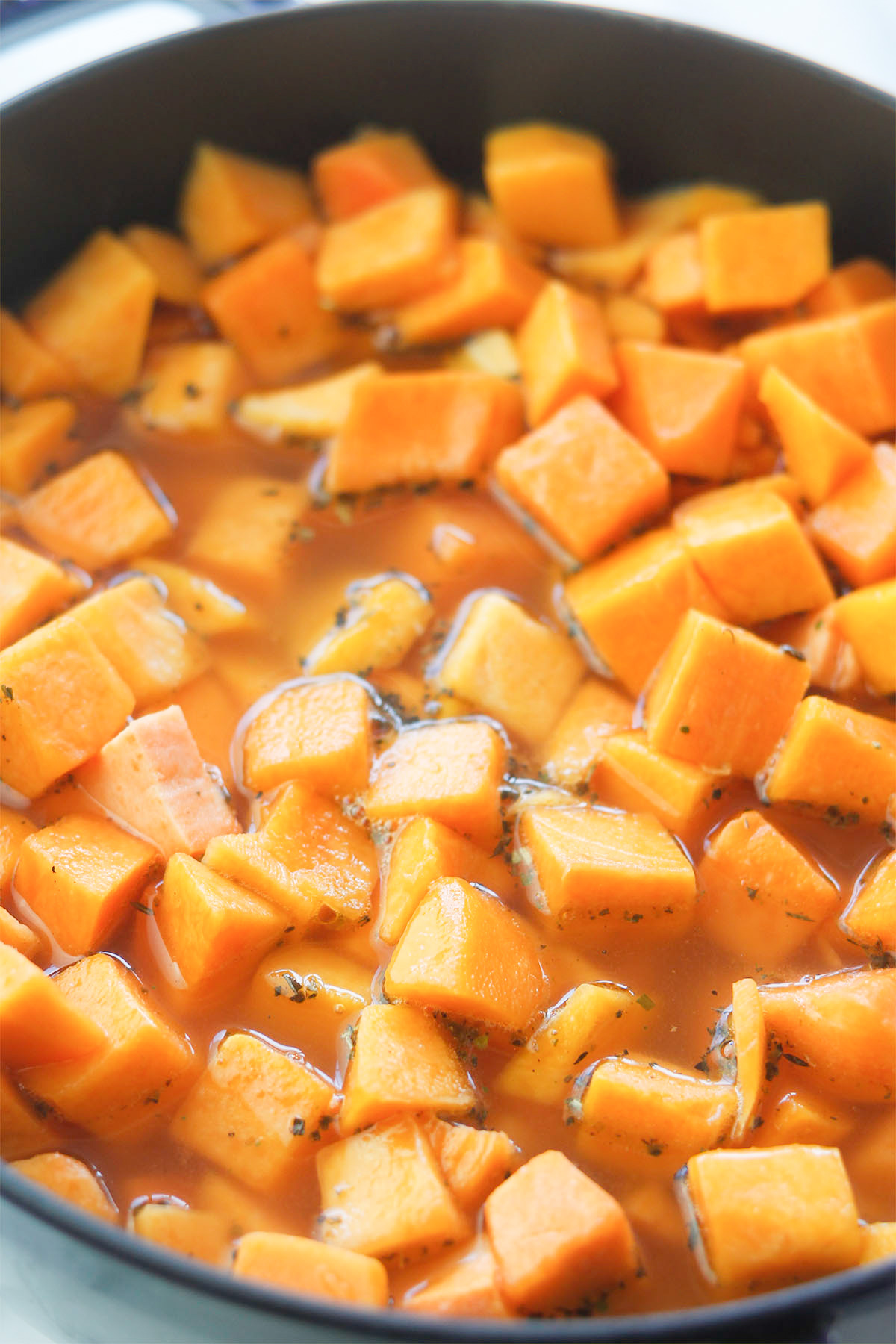Pot filled with butternut squash, sweet potatoes, carrots and chicken stock.