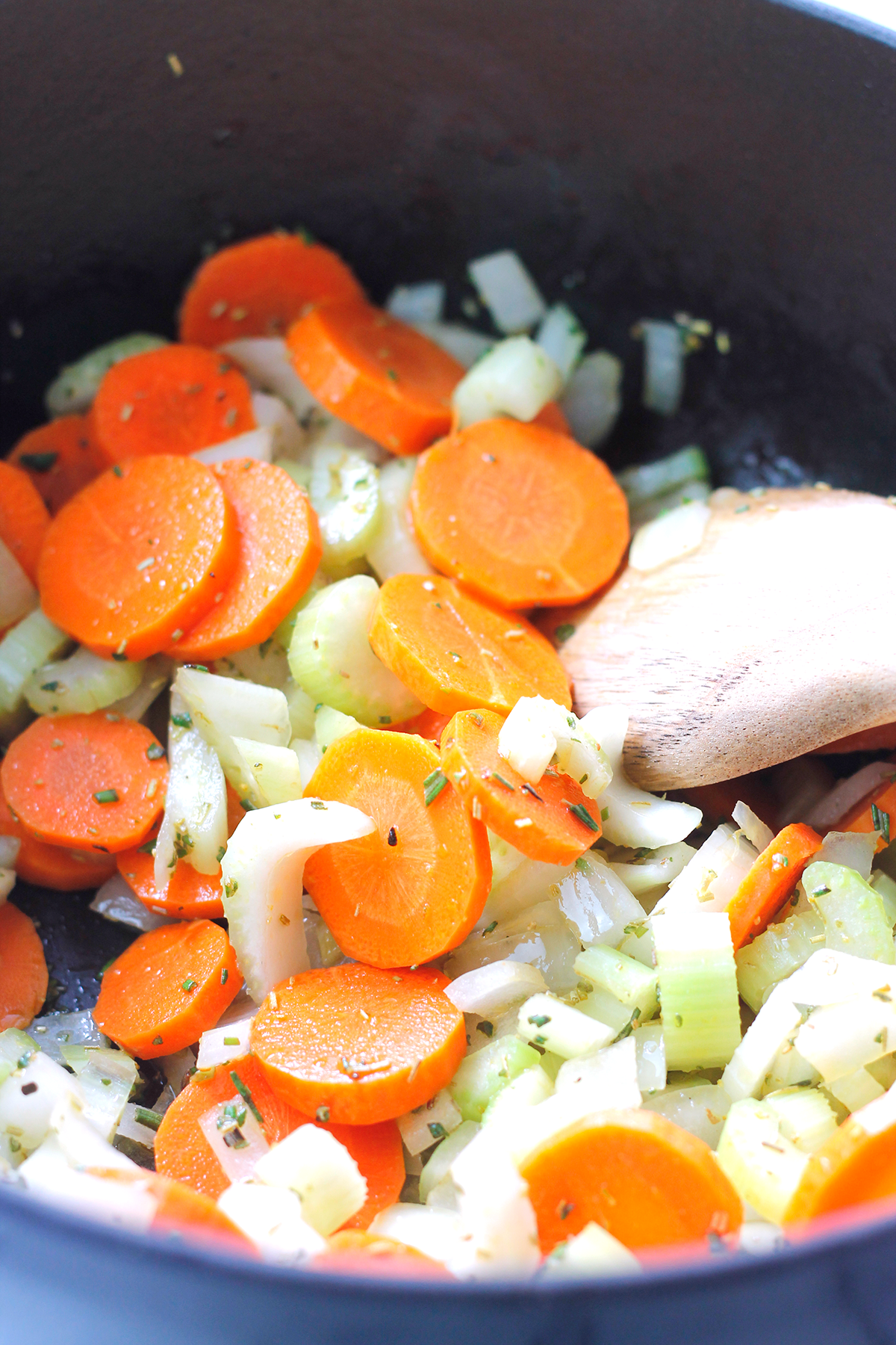 Sliced carrots, onions, and celery sauteing in pot.