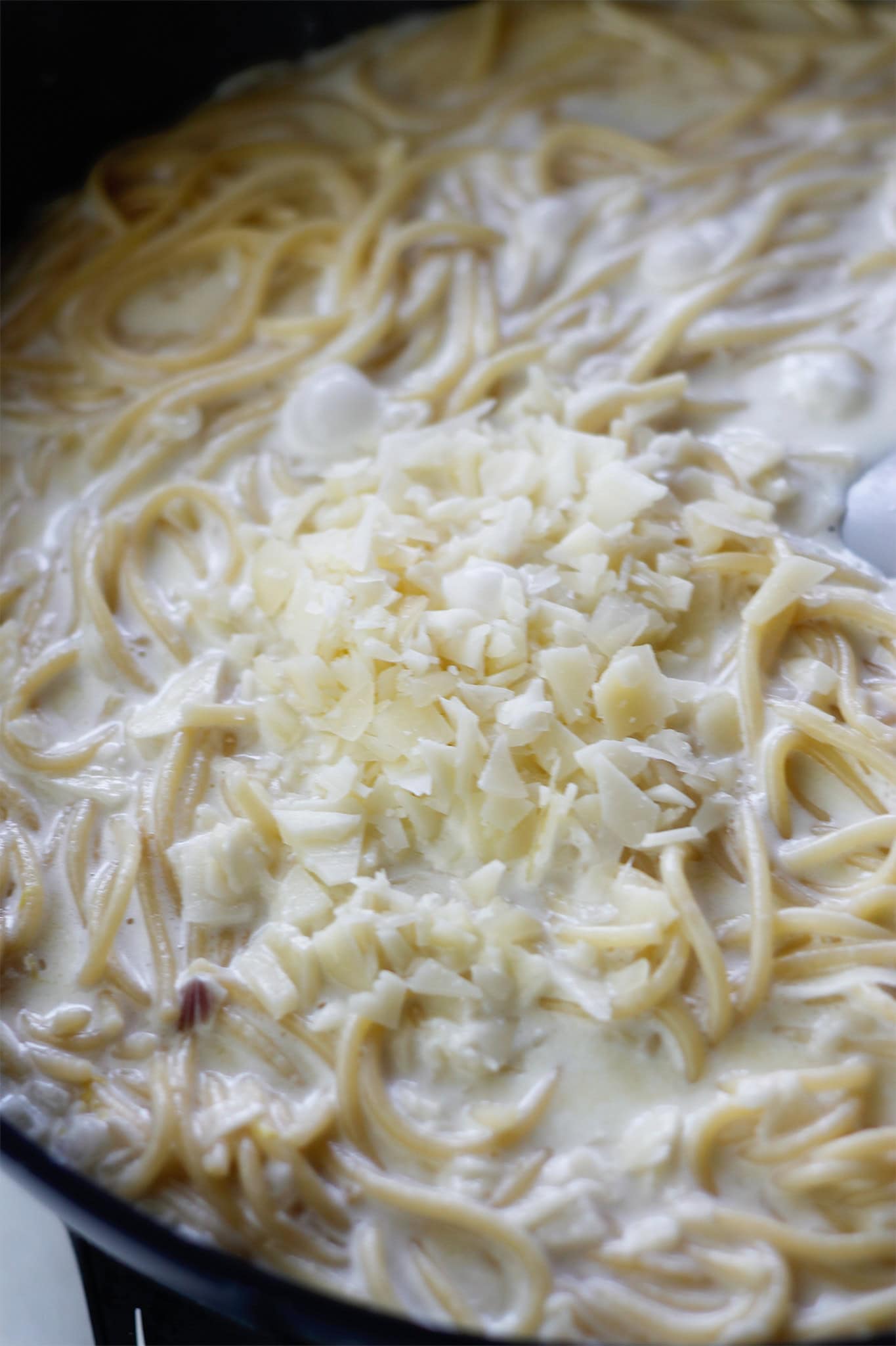 Adding cheese to pasta and cream sauce.