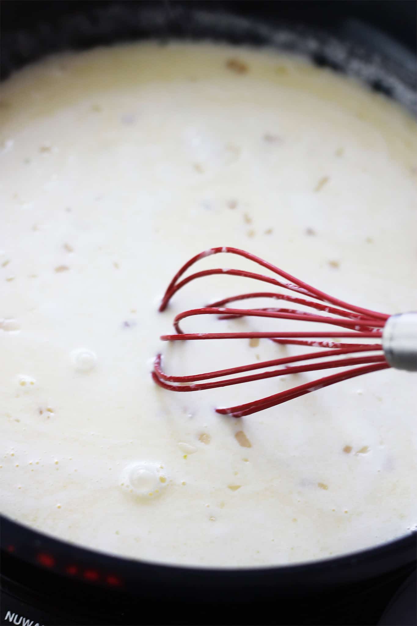 Whisking butter and cream together in pan.