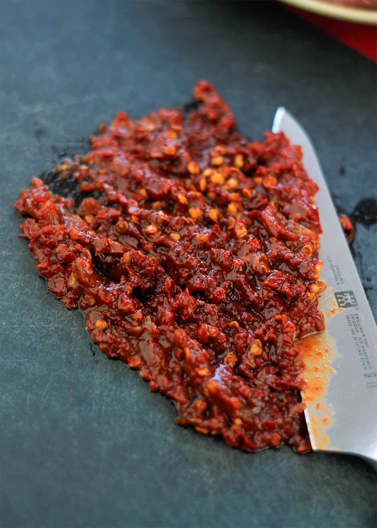 Chopped chipotle peppers on cutting board with a knife to the right of the chopped peppers