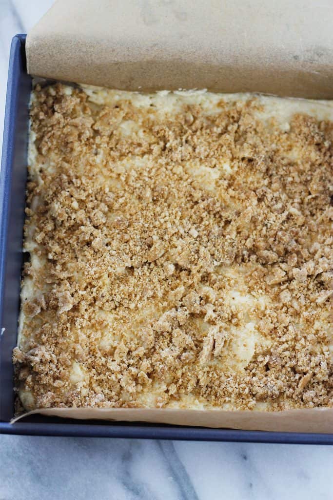 First crumb layer sprinkled over the top of the first layer of crumb cake batter of the lemon blueberry crumb cake.