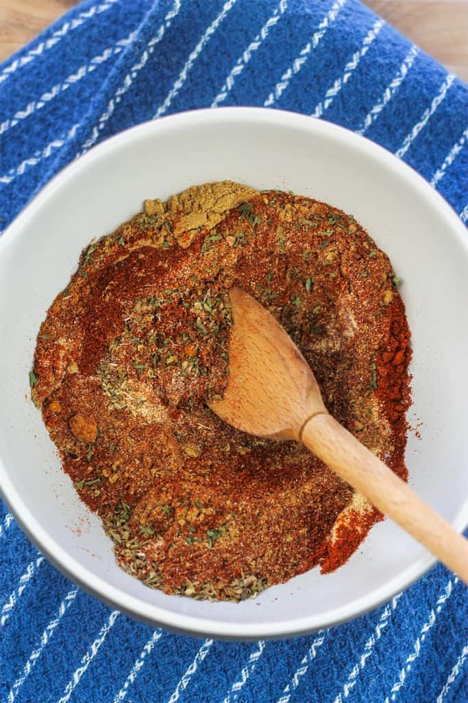 Taco seasoning in mixing bowl with wooden spoon.