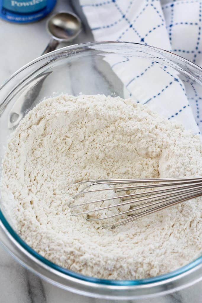 Dry flour mixture for the lemon blueberry crumb cake in a glass bowl with a silver whisk.