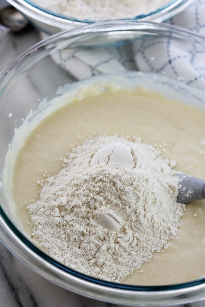 Overhead shot of on third of the flour mixture added to the liquid batter in a glass bowl.