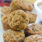 Batch of Chai Apple muffins on counter with a small spoon in front of muffins with chai sugar glaze on spoon.