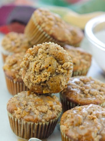 Batch of Chai Apple muffins on counter with a small spoon in front of muffins with chai sugar glaze on spoon.