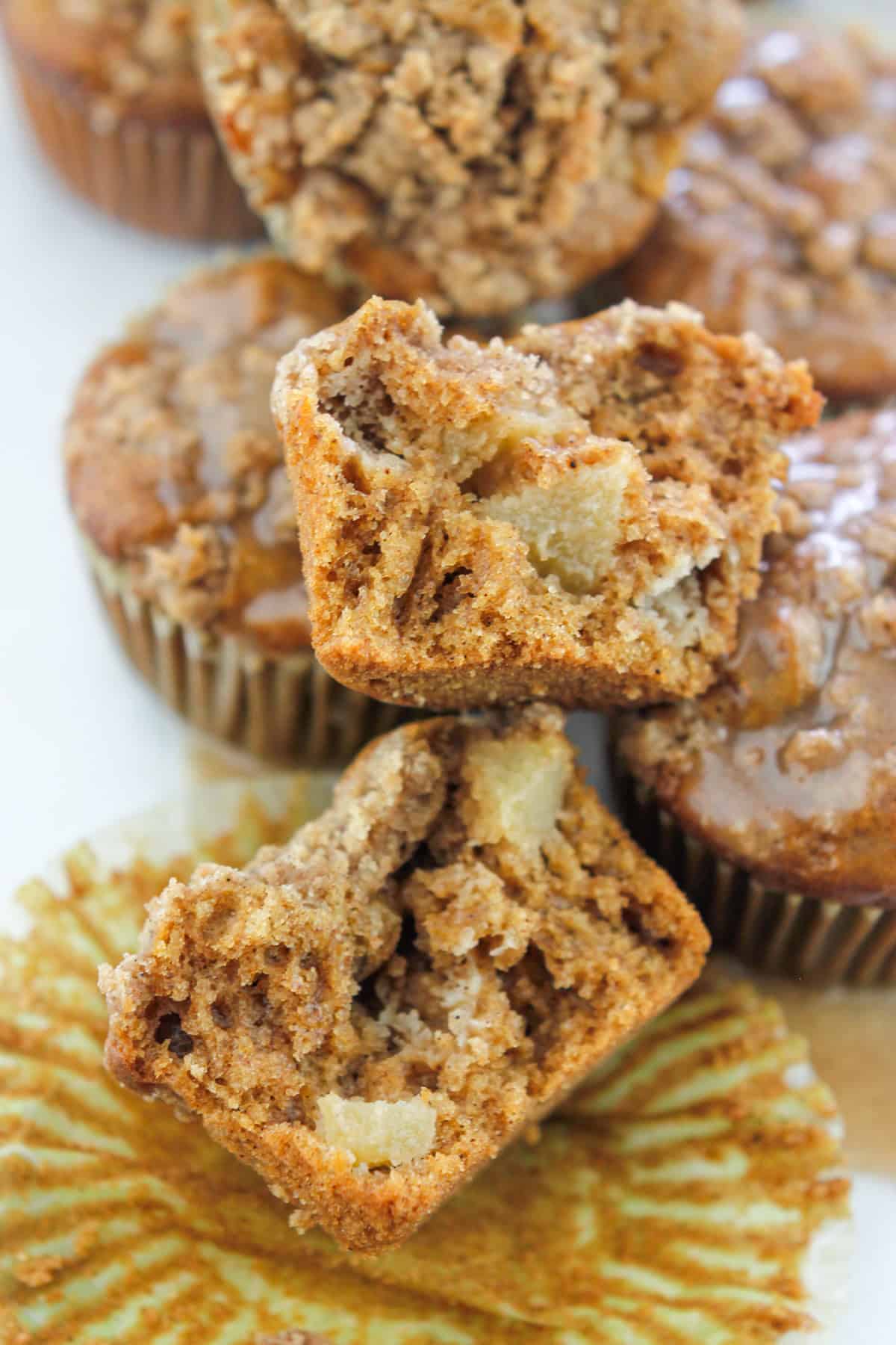 Close-up shot of a chai muffin torn in half showing the inside of the muffin with more muffins in the background.