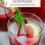 Overhead shot of hibiscus lemonade garnished with sliced lemon and fresh mint in a short glass.