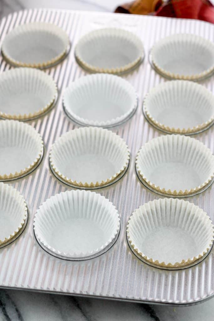 Silver muffin tin lined with white paper liners.